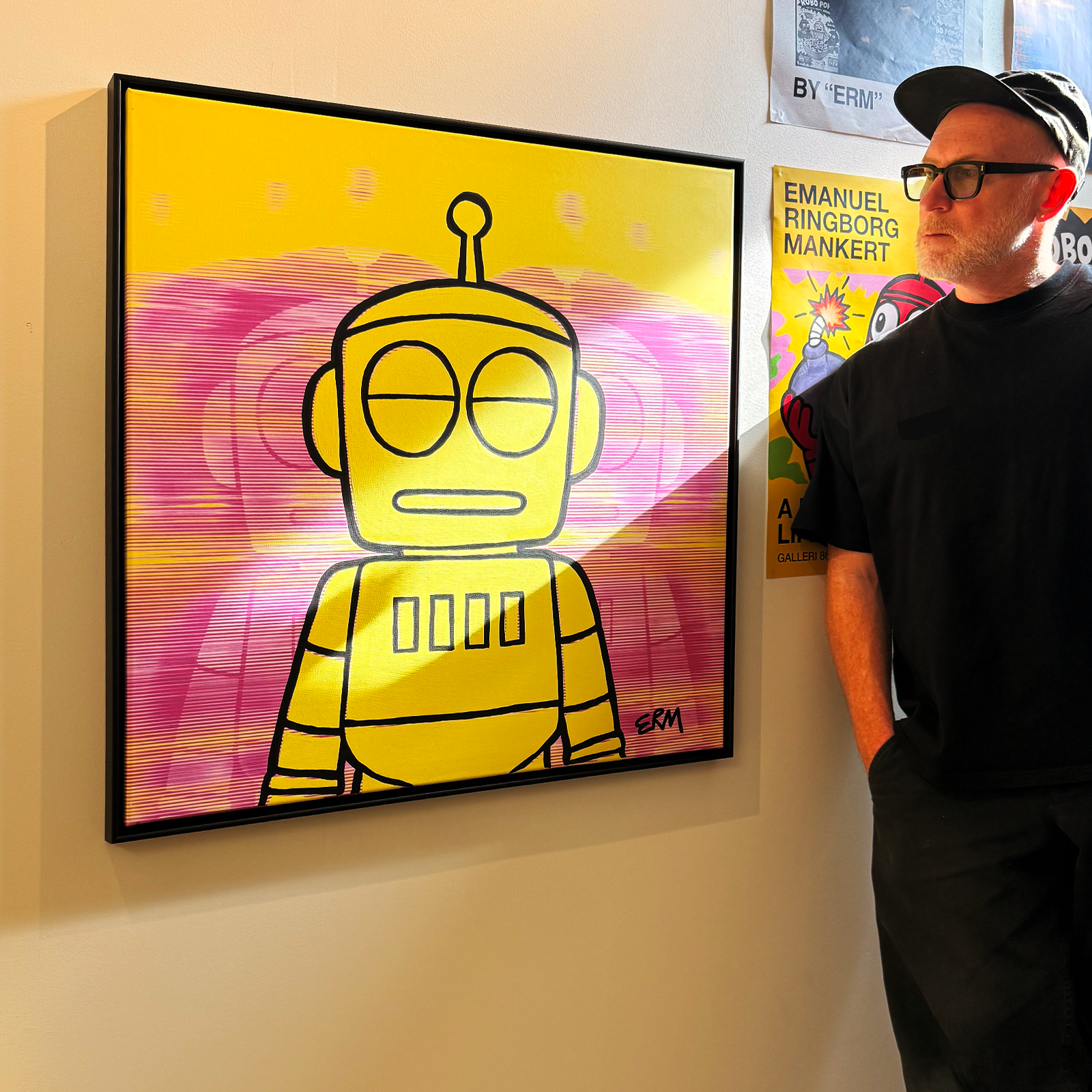 ERM beside a finished, framed yellow Robo Zero painting in the studio